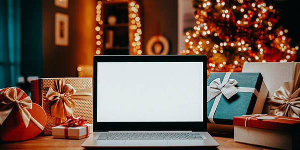 Weihnachtliche Stimmung mit Geschenken um einen Laptop herum