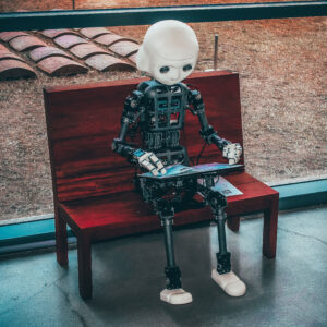 Ein Roboter der auf einer Bank sitzt und ein Tablet in der Hand hält