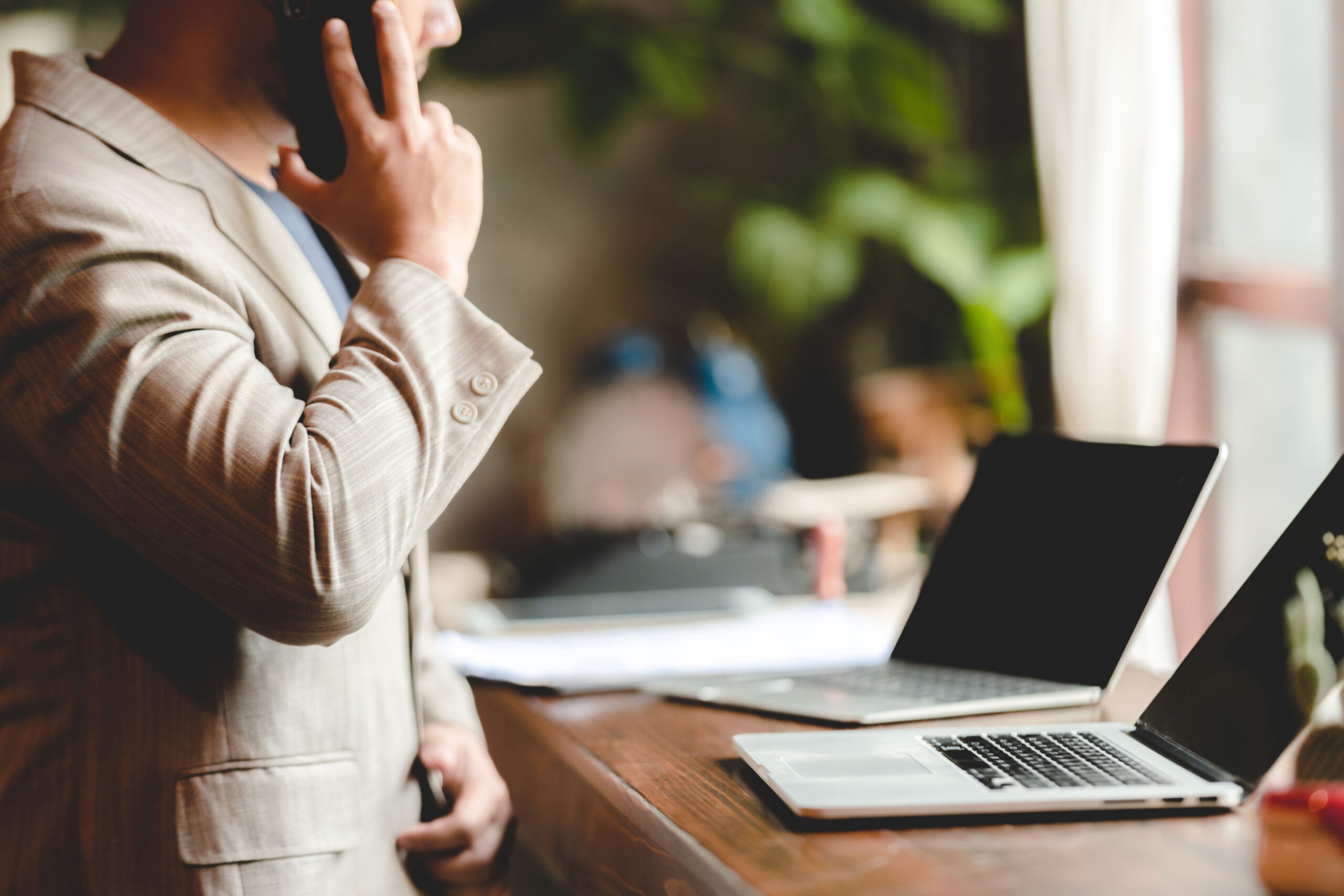 Mann telefoniert und hat zwei Laptops vor sich 