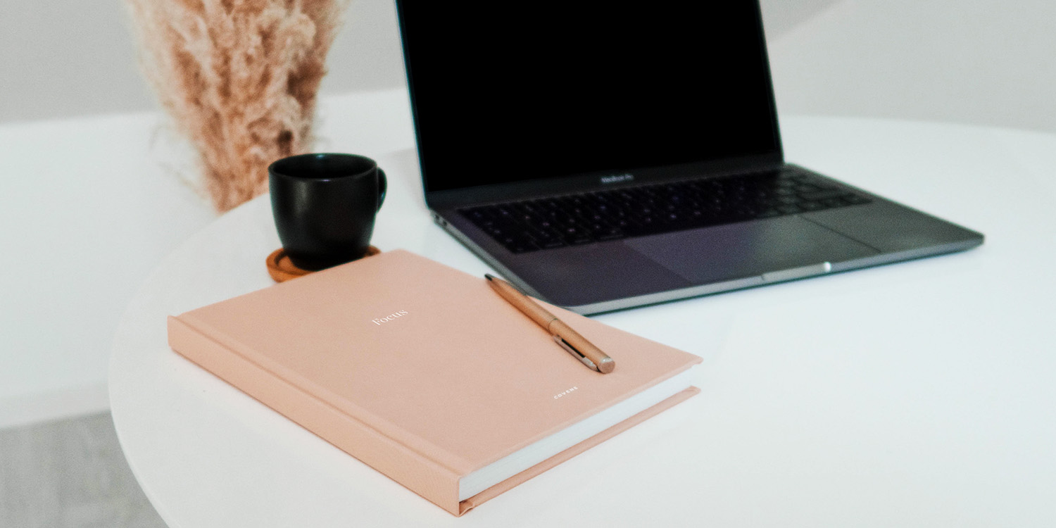 Laptop und Notizbuch auf einem Tisch