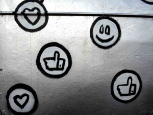weiße Like- und Emoji-Symbole auf silberner Wand